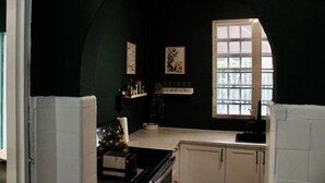 A dark green room with a window, a small table with a vase, and a cabinet. - Vintage Charm n Historic Miramar (San Juan)