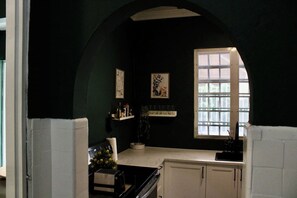 A dark green room with a window, a small table with a vase, and a cabinet.