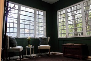 Una habitación con dos sillas, una mesita y un aparador de madera.