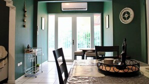 A dining area with a table, chairs, a clock, and an air conditioning unit. - Vintage Charm n Historic Miramar (San Juan)