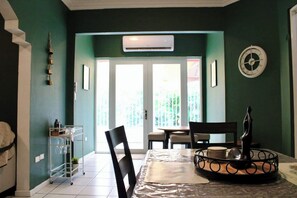 A dining area with a table, chairs, a clock, and an air conditioning unit.