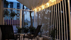 A covered outdoor seating area with a table and chairs, surrounded by vertical white railings and potted plants. - Vintage Charm n Historic Miramar (San Juan)