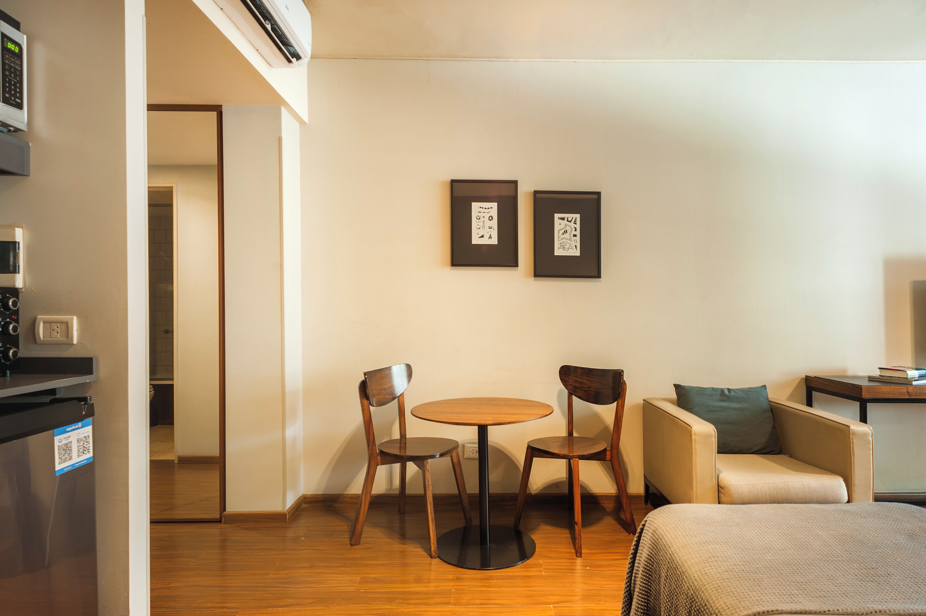 Ein Hotelzimmer mit Holzboden, einem runden Tisch mit Stühlen, einer Couch, einem kleinen Beistelltisch und zwei gerahmten Bildern an der Wand.
