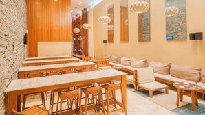 A modern hotel lobby with wooden tables and chairs, a seating area with sofas, and a stone wall. - Modern High End Studio Palermo T107 (Buenos Aires)