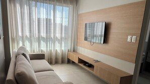 Una sala de estar moderna con un sofá, un televisor montado y una consola de madera.