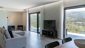 Una sala de estar moderna con un televisor de pantalla plana grande, un sofá y una mesa de comedor.