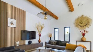 A modern living room with a flat-screen TV, a sofa, a coffee table, and a decorative vase. - House at the foot of the Alpilles (Saint-Rémy-de-Provence)