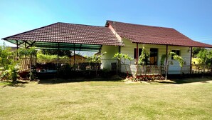 Une maison à deux étages, avec un toit recouvert de tuiles rouges et une terrasse couverte.