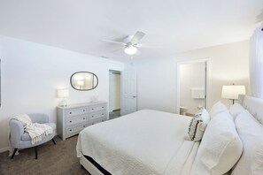 A bedroom with a bed, a dresser, a chair, a ceiling fan, and a door. - Rising Sun - Walk to the Beach! Secluded screened in Pool with Waterfall! (Naples)