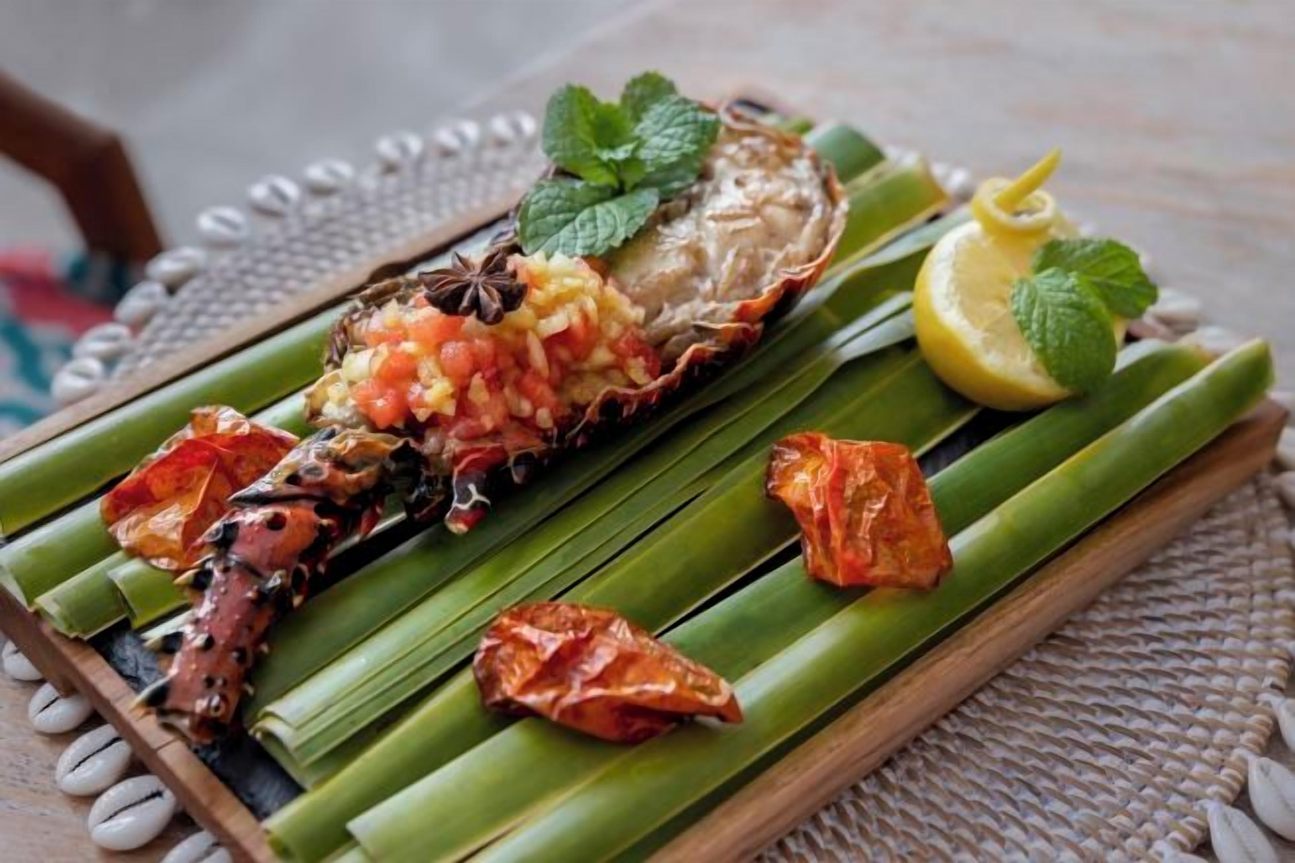 A seafood dish on a banana leaf with lemon and mint garnish.