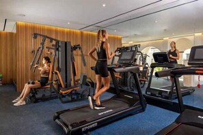 Un gimnasio con cintas de correr, una máquina de pesas y un espejo.