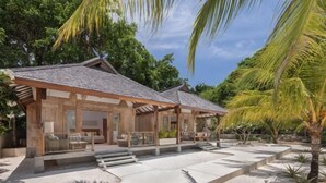 Un complexe hôtelier moderne doté d’un espace extérieur couvert avec des sièges, d’une piscine et d’un jardin tropical.