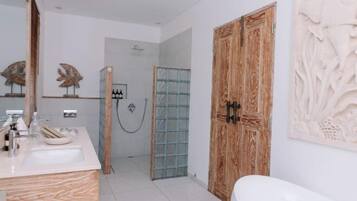A modern bathroom with a wooden door, a glass shower enclosure, and a marble sink.