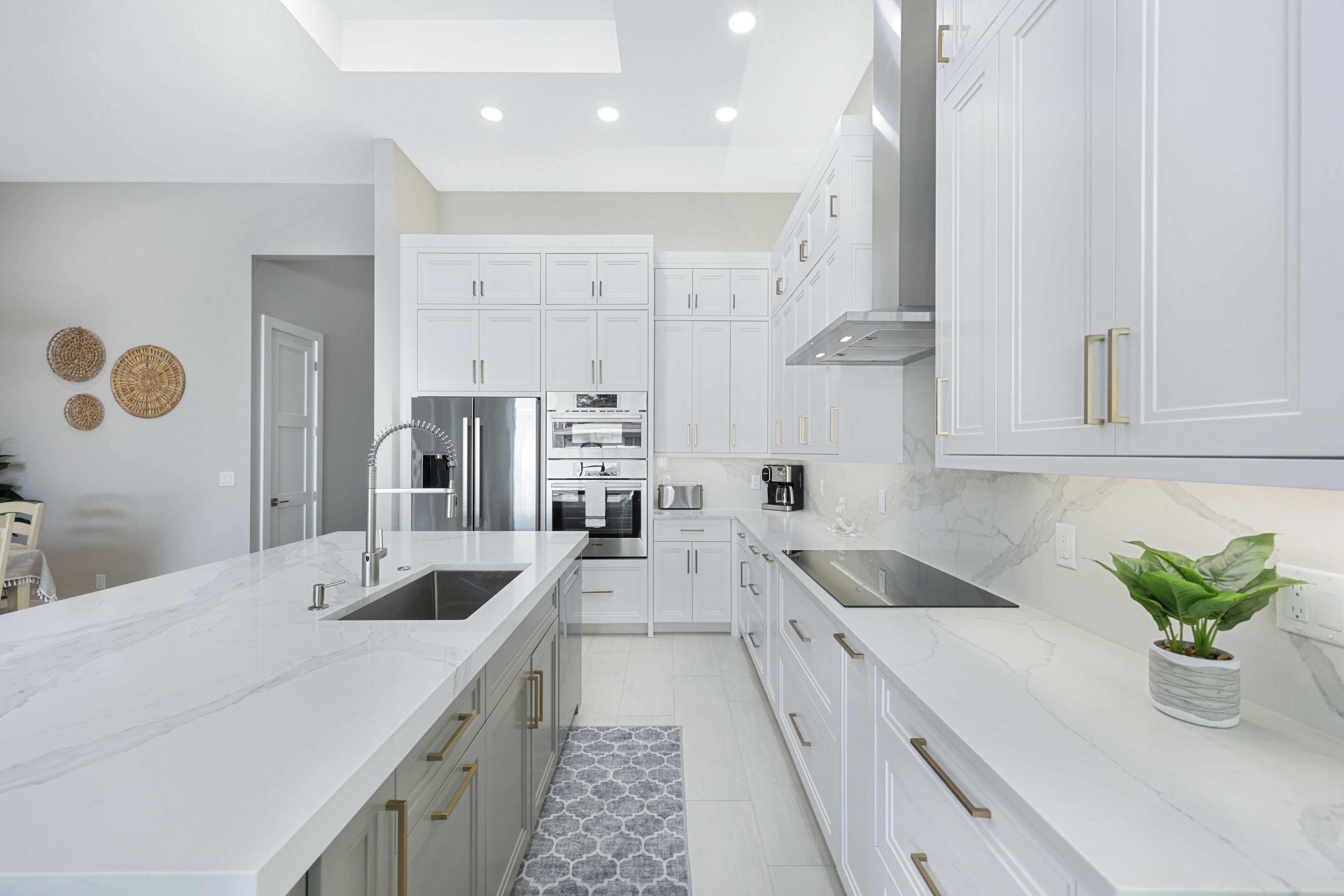Una cocina moderna con armarios blancos, electrodomésticos de acero inoxidable y encimera de mármol.
