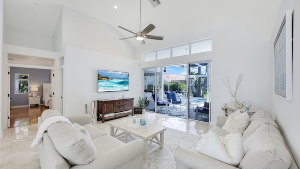A spacious living room with a large window, a ceiling fan, and a view of the outdoors.