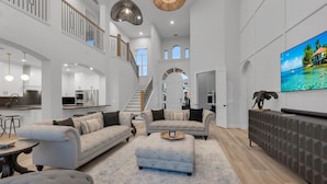 A spacious living area with a high ceiling, a staircase, and a kitchen in the background. - Tropical Oasis! - Luxury Canal Home! 1 Mile To The Beach! Heated Pool & Spa (Naples)