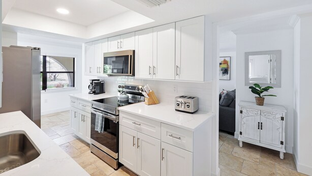 A modern kitchen with white cabinetry, stainless steel appliances, and a built-in microwave. - Sea La Vie - Pickleball close by, Heated Pool, Walk to Beach! (Naples)
