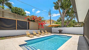 A rectangular swimming pool with tiled edges, surrounded by beige tiles and a white fence. - Sea La Vie - Pickleball close by, Heated Pool, Walk to Beach! (Naples)