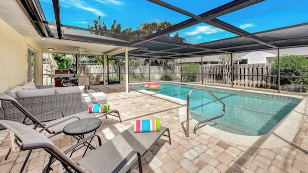 Ein überdachter Außenbereich mit Pool, Liegestühlen und einem Patio-Tisch.