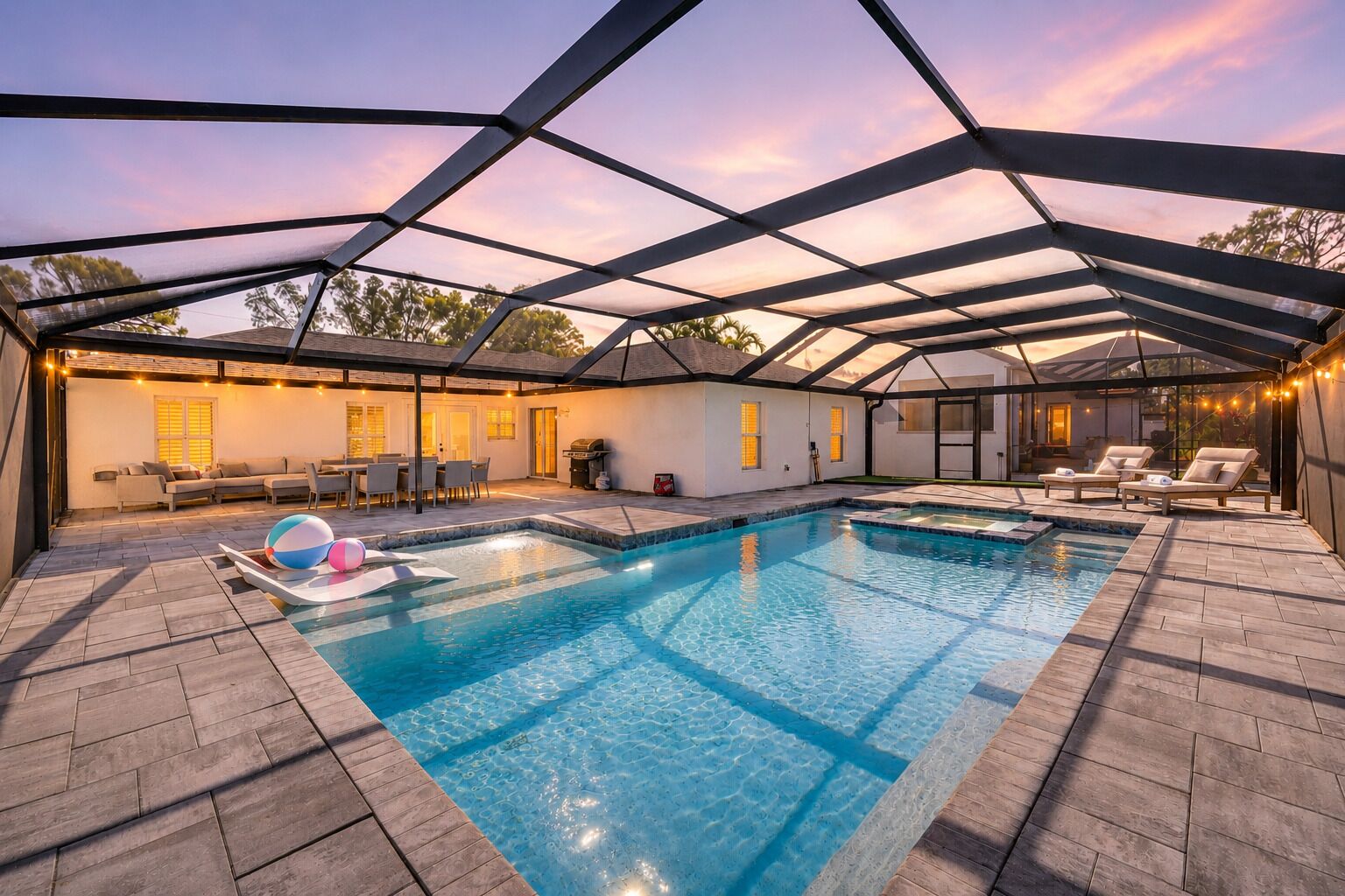 Un área de piscina con dos piscinas, sillas de descanso y un porche cubierto.