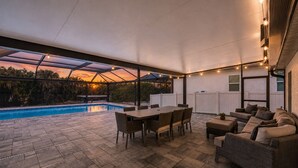 An outdoor patio with a pool, a table, and a sofa.