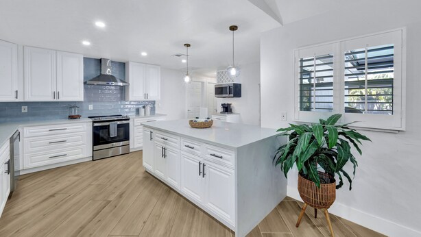 A modern kitchen with white cabinetry, stainless steel appliances, and a central island.