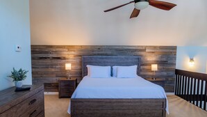 A bedroom with a wooden headboard, a ceiling fan, bedside lamps, a dresser, and a nightstand.