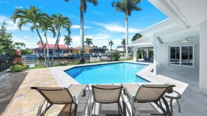 A swimming pool with lounge chairs and palm trees, surrounded by a patio area. - Sunny Side! – Southern Exposure - Heated Saltwater Pool! Walk to Beach! (Naples)