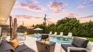 A backyard with a swimming pool, outdoor furniture, and a fire pit.