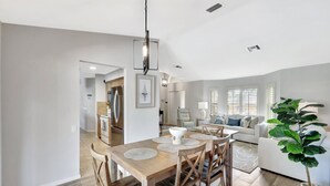 A spacious living area with a dining table, chairs, and a large plant.