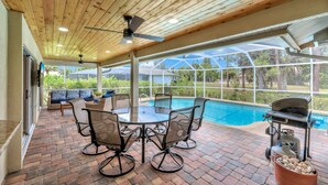 An outdoor patio with a pool, wooden ceiling, and seating area.