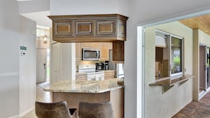 A kitchen with a granite countertop, two bar stools, and wooden cabinets.