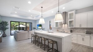 A modern kitchen with a large island, bar stools, and white cabinetry.