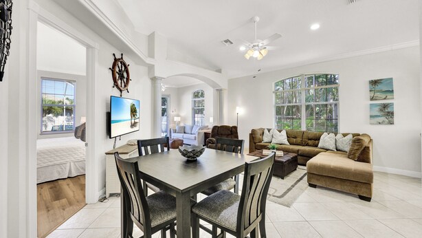 A spacious living area with a dining table, sofas, and a TV. - New! Sunkissed - 1 Mile to Beach! Heated Pool! (Naples)