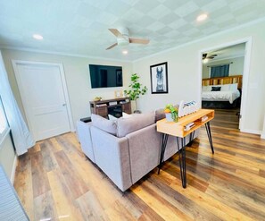 Un salon avec un canapé, une table basse et un téléviseur fixé au mur.