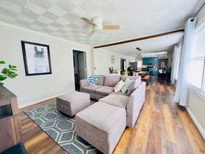 A living room with a sectional sofa, ottoman, and a ceiling fan.