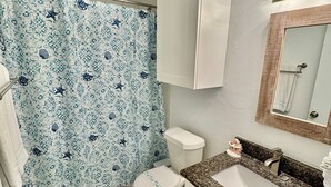 Une salle de bain avec des toilettes, un lavabo et un rideau de douche.
