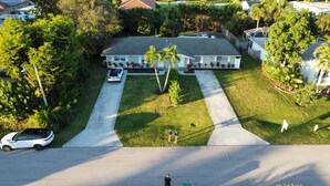 Uma casa residencial com entrada por meio de um acesso para carros, gramado e um pequeno jardim.