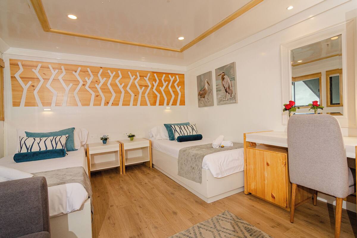 Quarto moderno com cama, mesas de cabeceira, escrivaninha e uma cadeira.