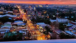 A cityscape at dusk with a prominent road running through the center, surrounded by buildings and construction sites. - Bella Suite Bacolod (Bacolod)