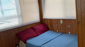 A compact RV bedroom with a bunk bed, wooden walls, and a small kitchenette.