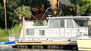A houseboat docked at a pier with a large chimney, surrounded by lush greenery and trees. - Maggie Jo’s paradise on the river ! (Georgetown)