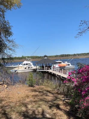 Un quai avec des bateaux, un kiosque et une rive bordée d’arbres.