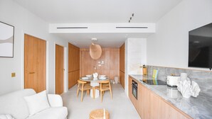 Eine moderne Küche mit Holzausstattung, ein Essbereich mit rundem Tisch und ein weißes Sofa.