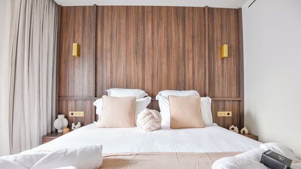 Ein Hotelzimmer mit einem Holz-Kopfteil, weißer Bettwäsche und einem Nachttisch mit Lampe und Dekoration.