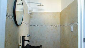 A bathroom with a black sink, a mirror, and a shower.
