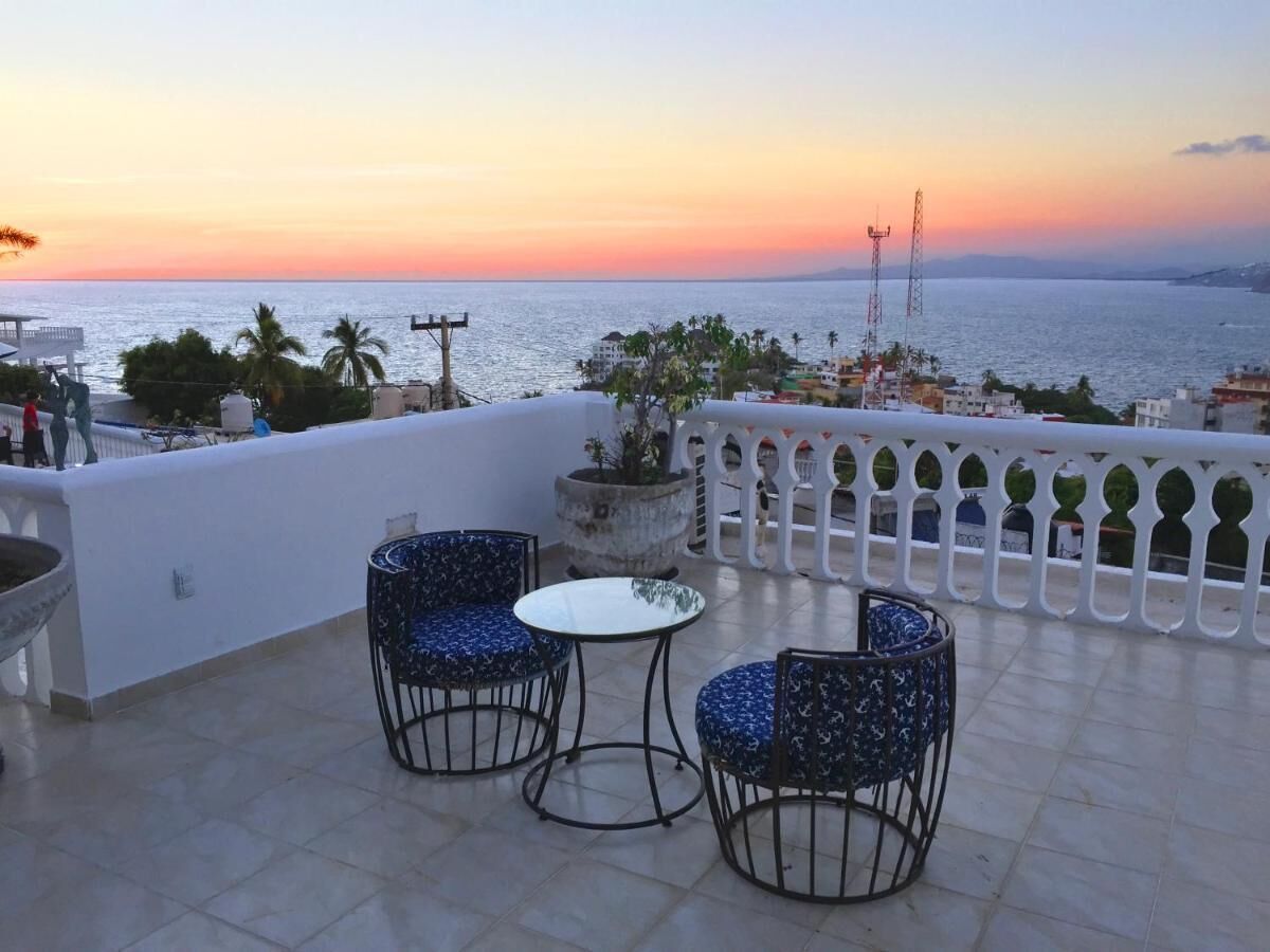 Terraza con dos sillas y una mesa, con vista a un cuerpo de agua al atardecer.