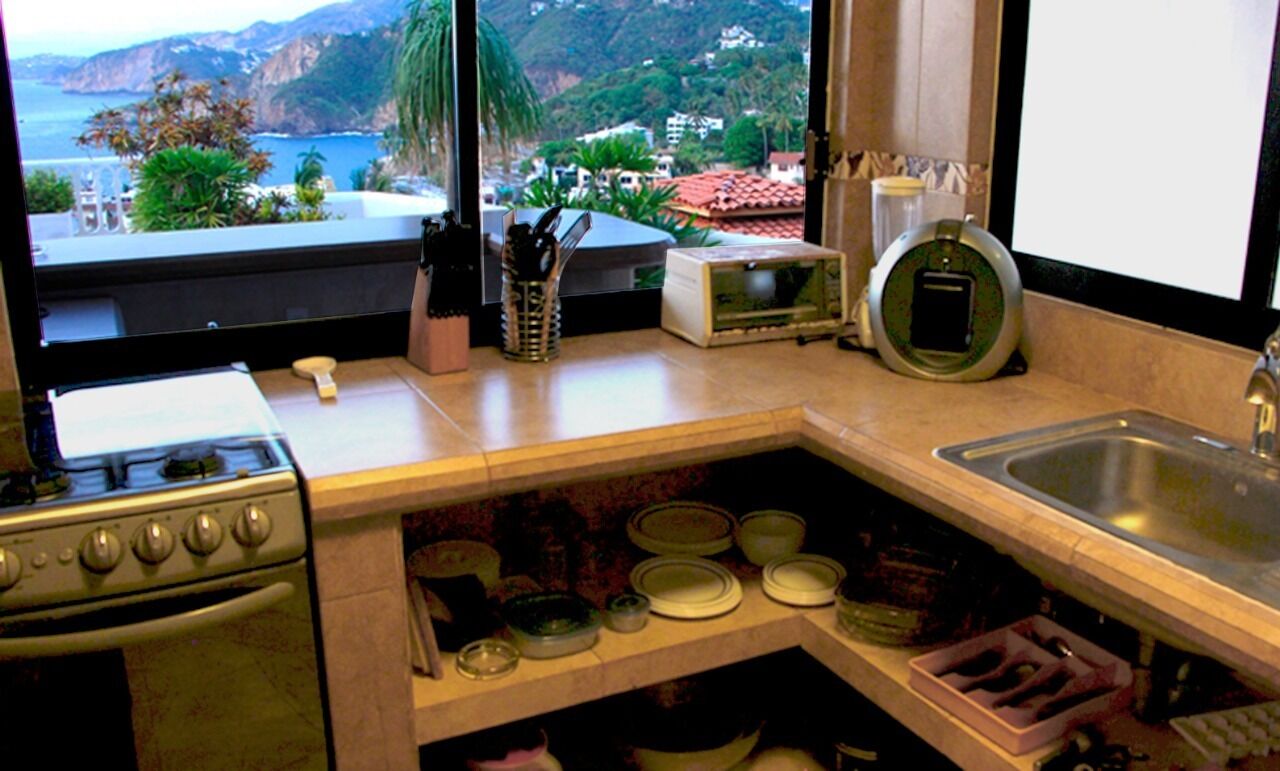 A kitchen with a stove, sink, and various kitchen items.