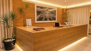 Una recepción con detalles de madera, una fotografía enmarco de un paisaje urbano en la parte superior y un interior moderno y bien iluminado.