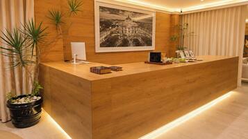 A reception desk with a wooden finish, a framed cityscape photograph above it, and a modern, well-lit interior.